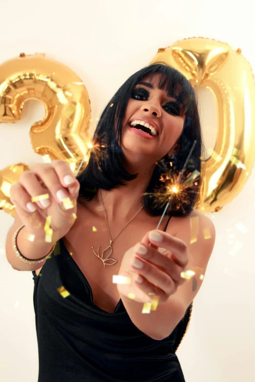 a woman holding two large numbers, one in the air and a sparkler