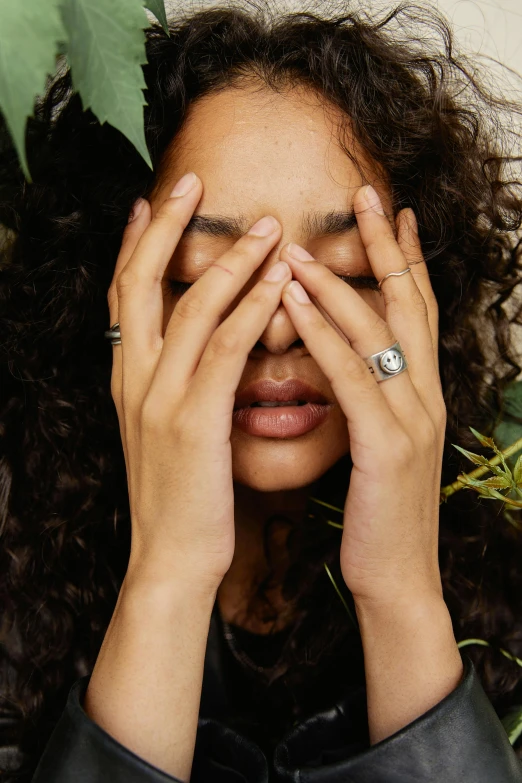 a woman holds her hands to her face with one hand on top of her nose