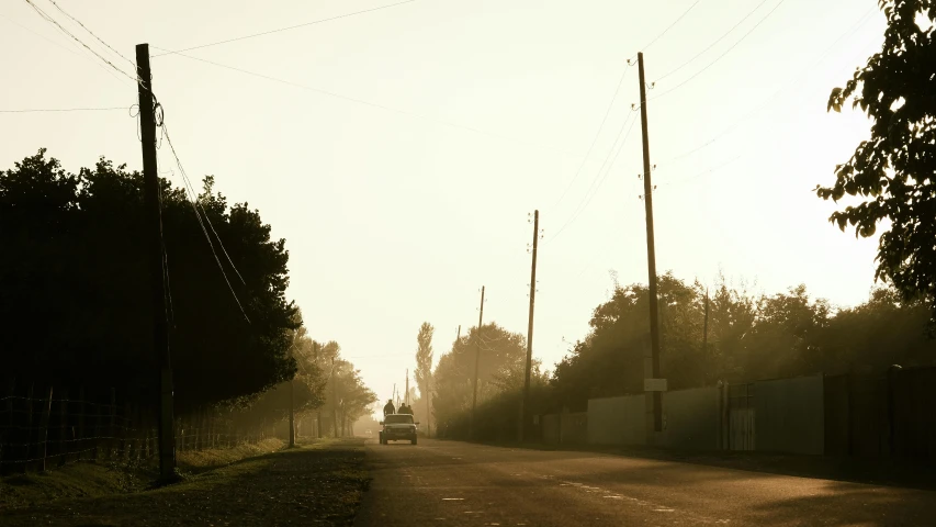 a foggy street with a car driving down the road