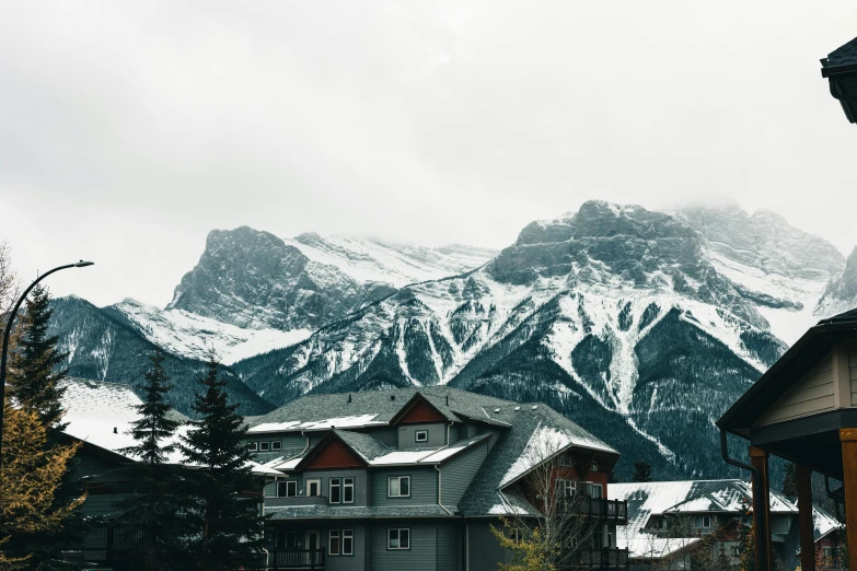 a snowy mountain range is seen behind buildings