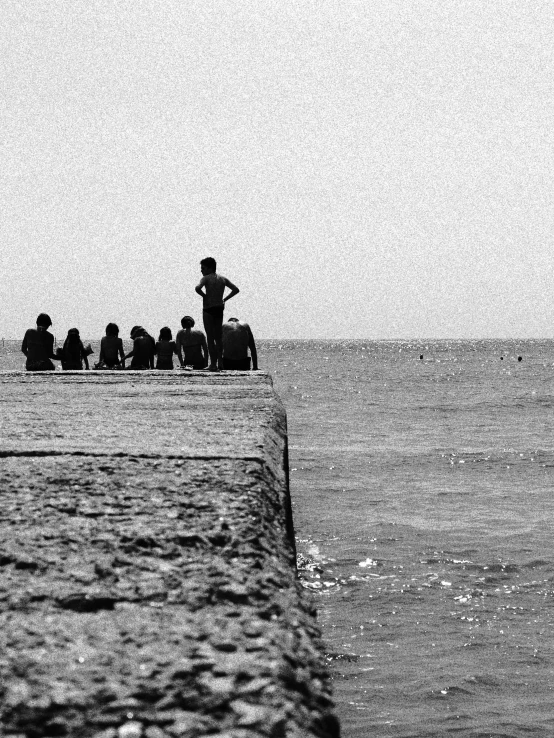 some people watching a boy riding a surfboard on the water