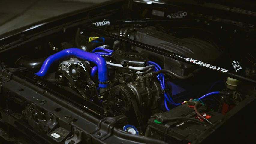 the engine compartment of a car with blue hoses and spark