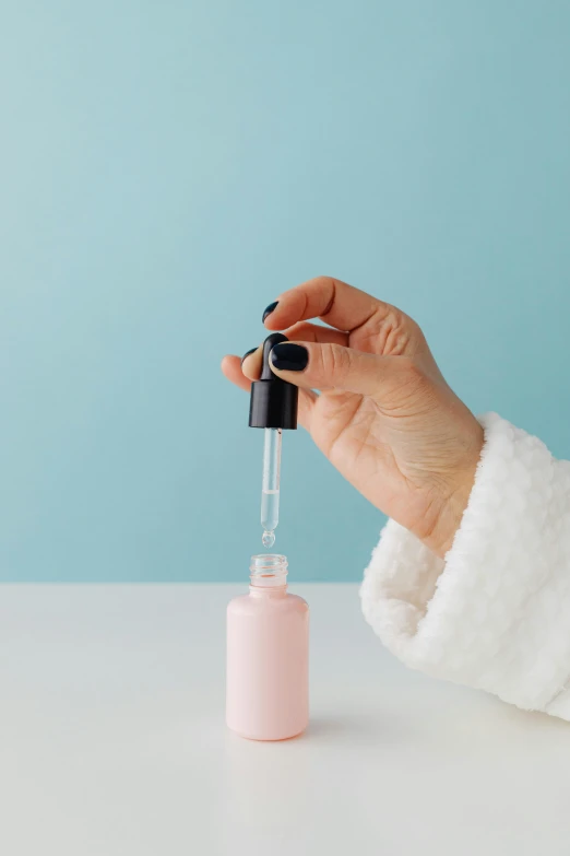 someone holding an empty glass bottle with the top filled with liquid