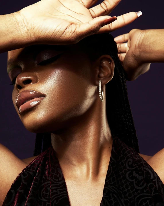 a young woman covers her face with one hand while she adjusts her earrings