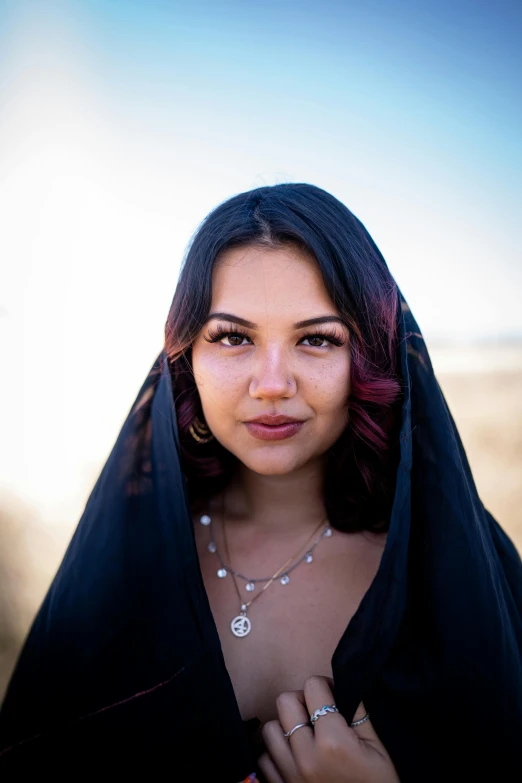 a beautiful woman wearing a black jacket standing near a field