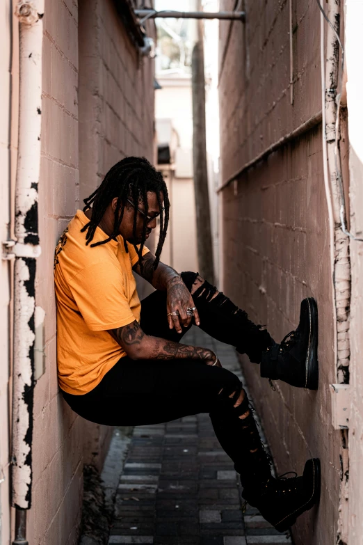 a man in a yellow shirt and black pants with dreadlocks
