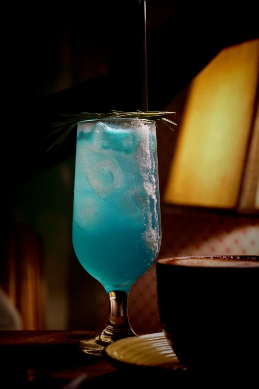 a blue drink in a glass next to a table