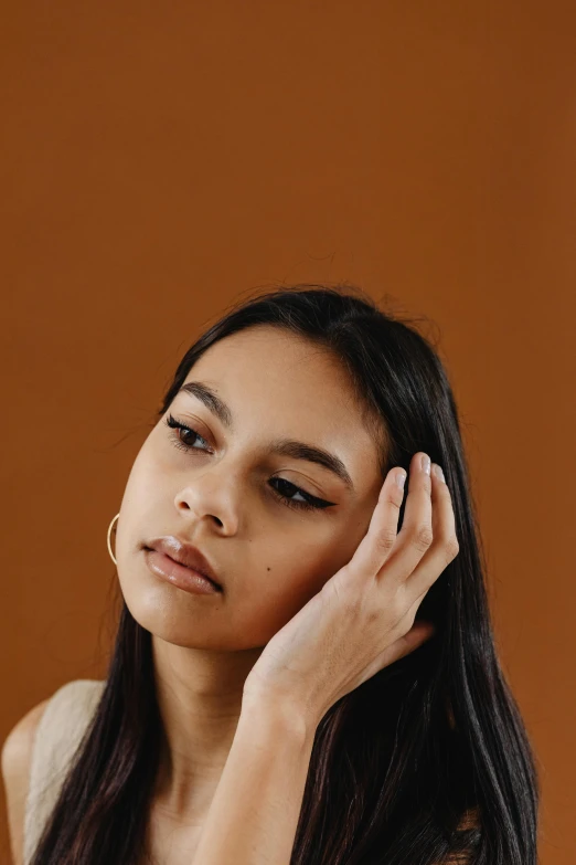 a woman sitting down with her hands near her ear