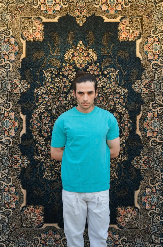 the young man poses in front of a carpet covered in flowers