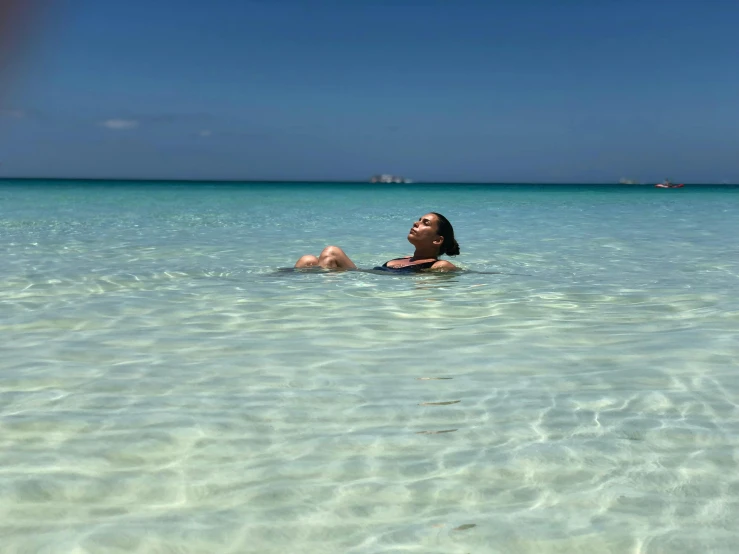a woman sitting in the middle of clear ocean water