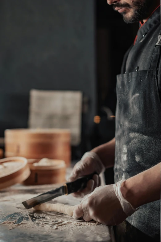 a person wearing gloves and making soing using bread dough