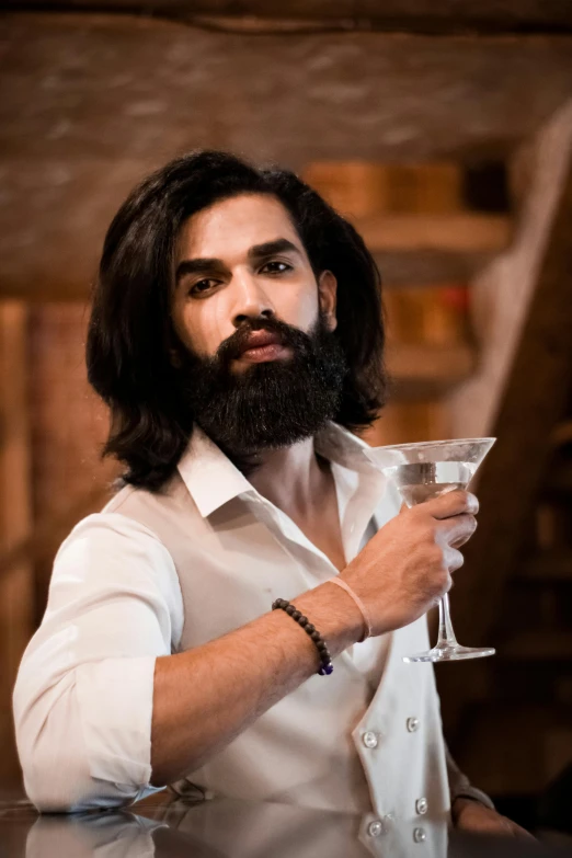 a man holds up a cocktail glass to his left