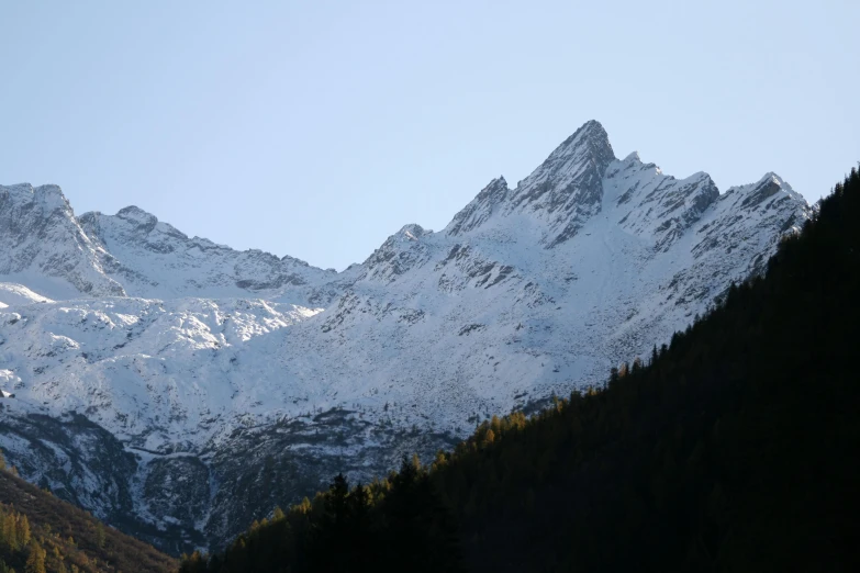 the snowy mountains are covered in pine trees