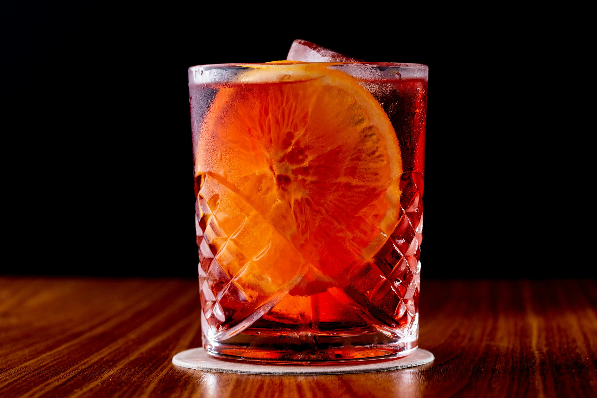 a picture of an orange slice and a drink on a wooden table