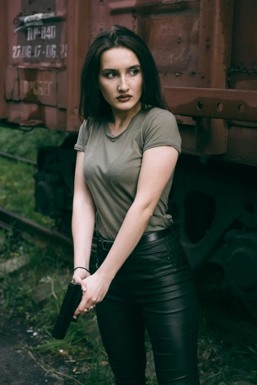 an asian woman poses with a gun beside a train