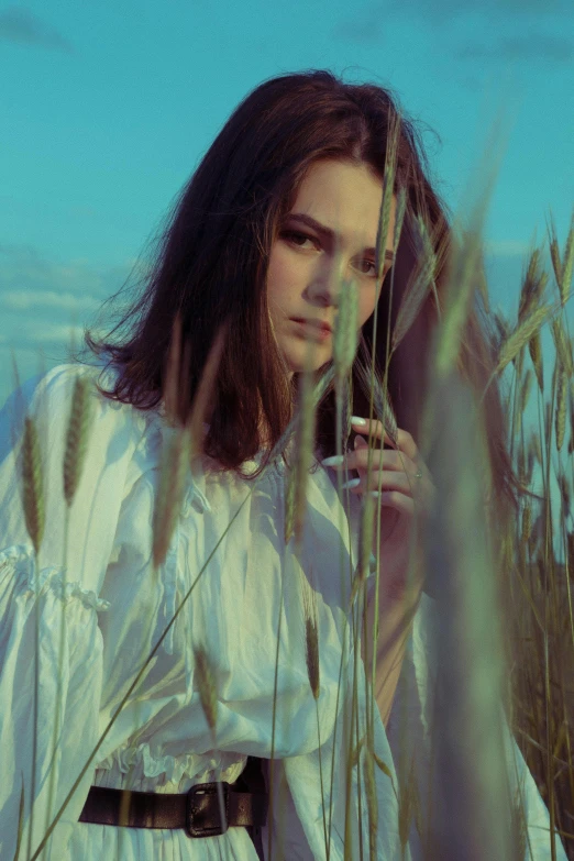 a woman stands in a field while looking at her phone