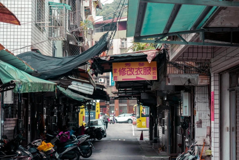 a narrow alley lined with colorful umbrellas next to parked motorcycles