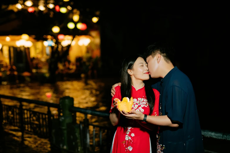 a couple are sharing a kiss by an open air area in the city at night