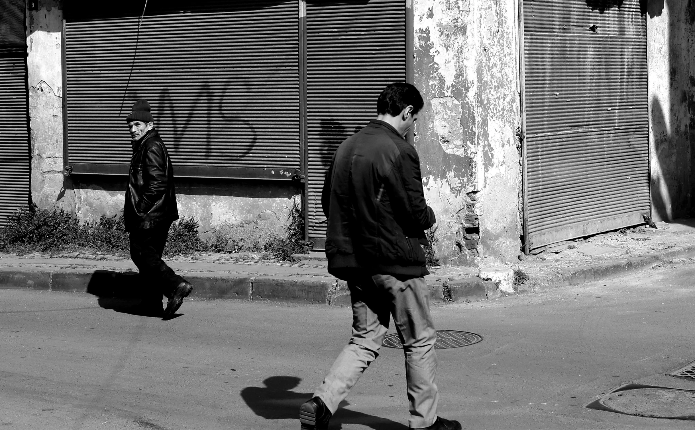 two men walking down the street in black and white