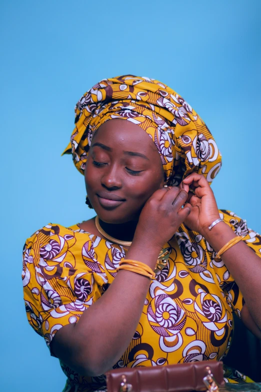 a woman in a yellow and purple patterned dress holding her phone to her ear