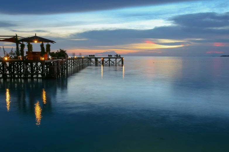 a pier that has lights on the water at night