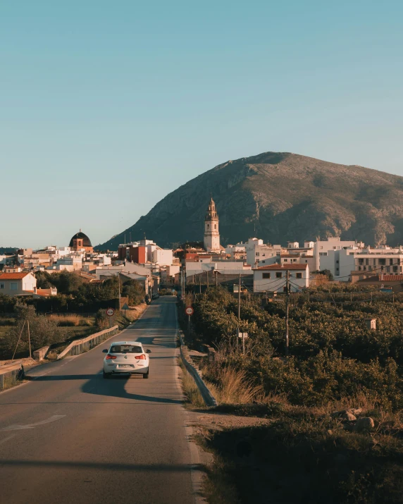 cars are traveling down an empty road near a hill