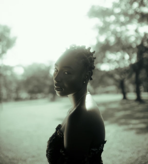 a woman wearing large hair standing in front of a tree