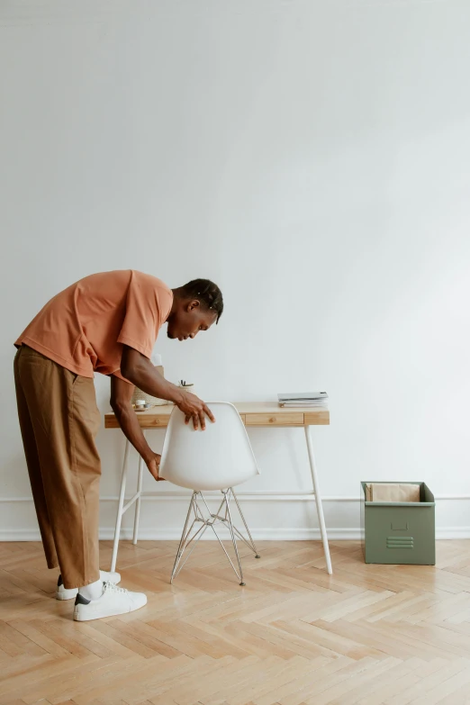 a man standing over a small table with a white chair