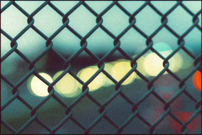 blurry pograph of cars on a road through a chain link fence