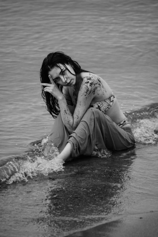 the woman is sitting on the shore looking in to the water