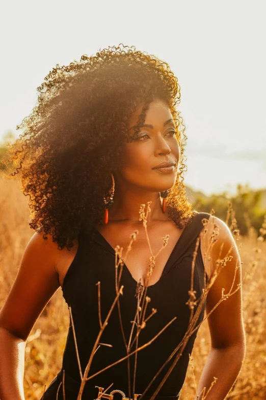 a woman with a black top is standing among weeds