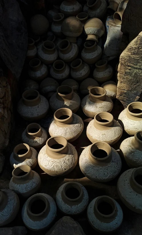 a bunch of brown ceramic pots next to a rock