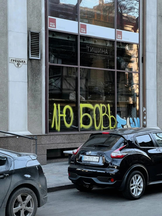 a street scene with cars parked and graffiti on the window