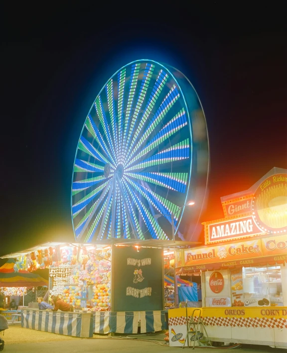 a large ferris wheel next to an apple stand at night