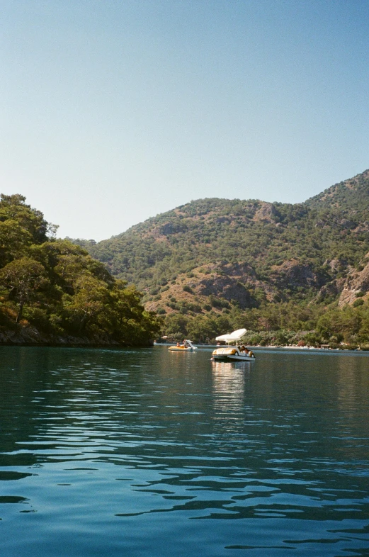 a view of the mountains in a lake near some boats