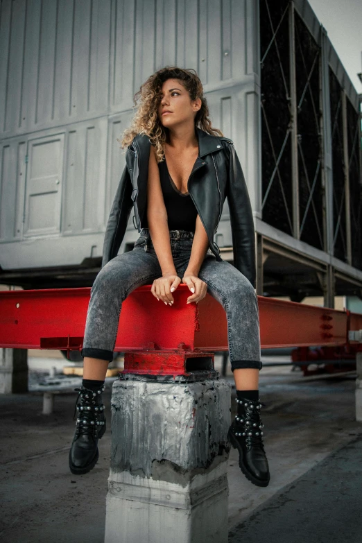 a woman sitting on a stool while wearing black boots