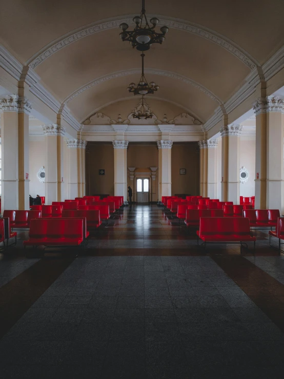 a set of chairs with red covers sitting in a hall