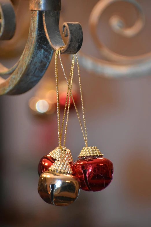 two red and gold bell ornaments attached to a hook