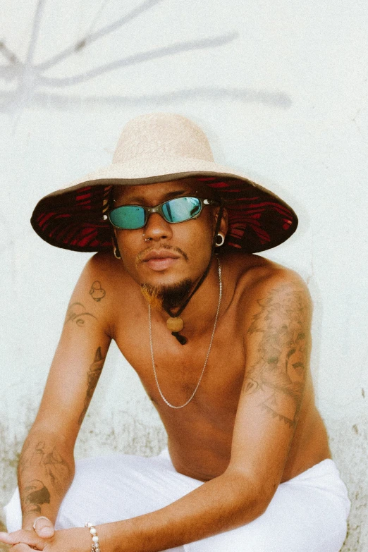 a man wearing a hat and sunglasses sitting down