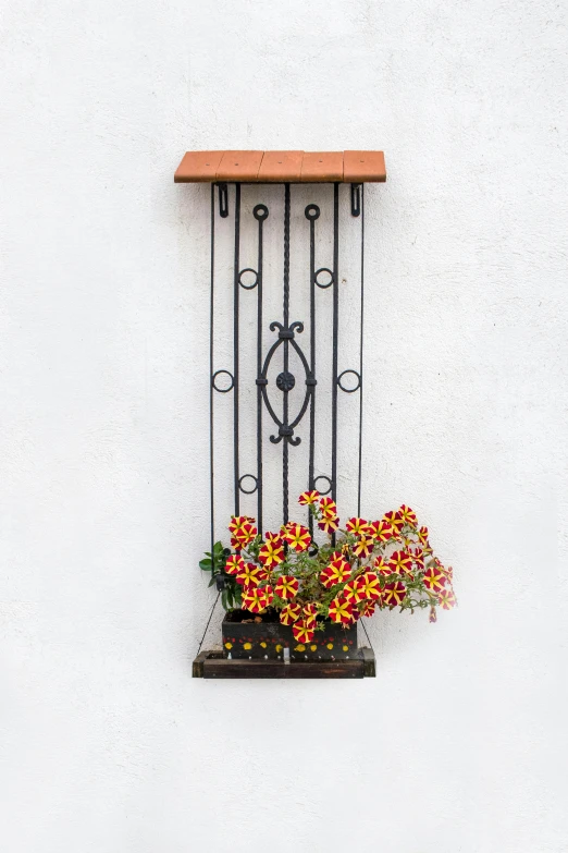 a window on the side of a white wall with a planter full of flowers