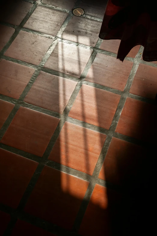 the shadow of a person on an orange tiled floor