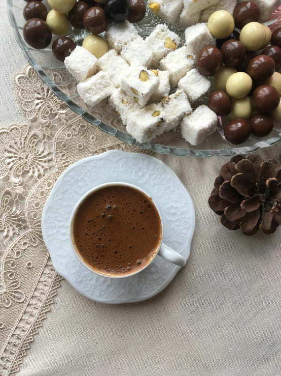 a cup of  chocolate sits next to a plate of cookies