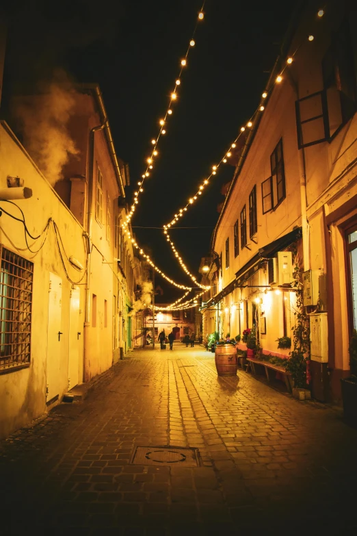 a cobblestone street filled with light strung overhead