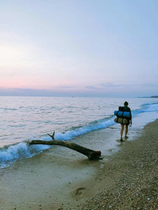 two people walking on the beach by the water