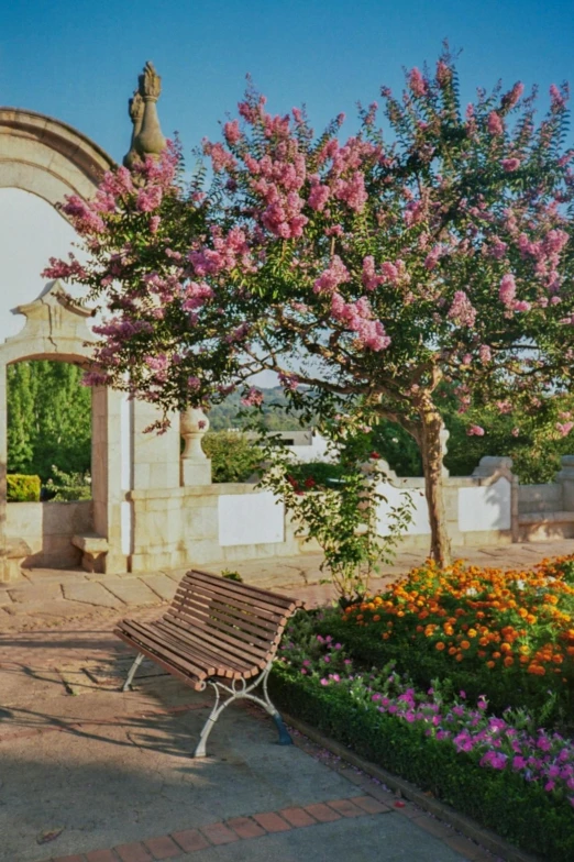 a wooden bench next to a white walled building