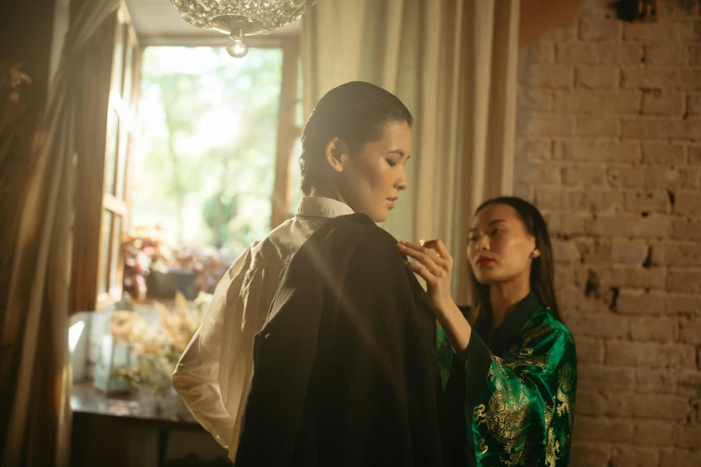two women, one wearing chinese clothing, are in the middle of a room