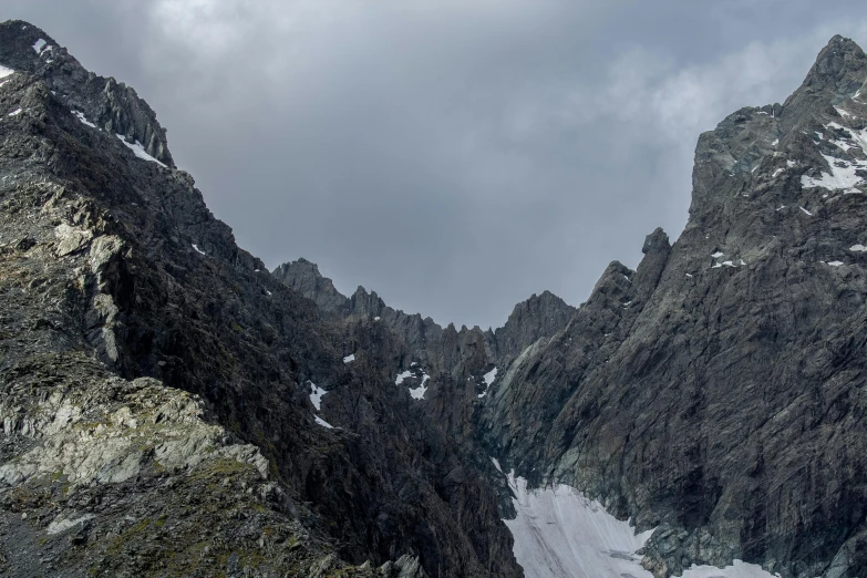 a mountain range with snow, rocks and grass on the ground