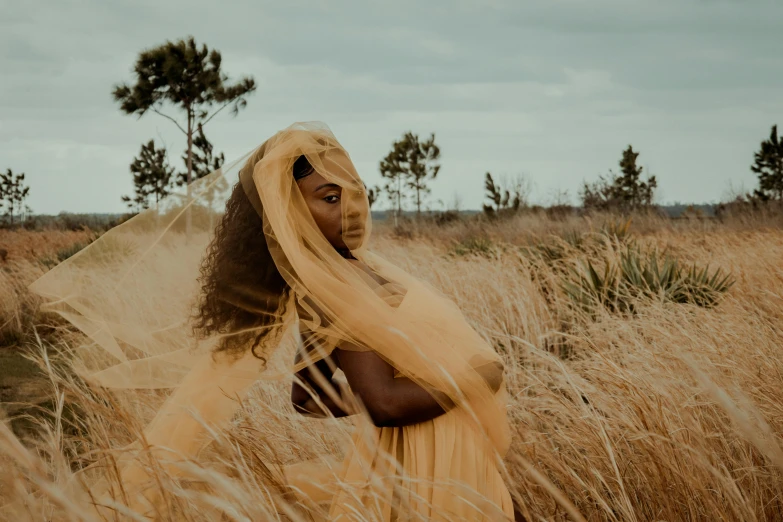 a woman with veils on standing in tall grass