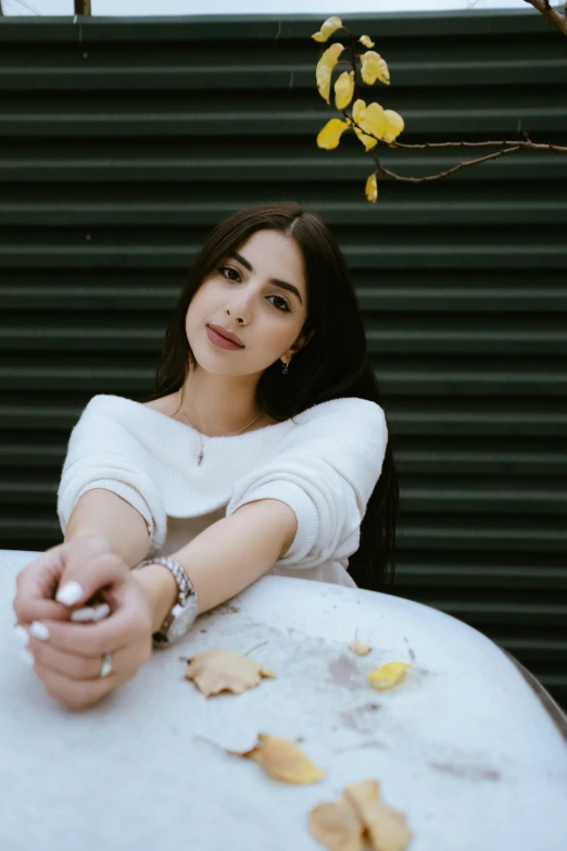 a woman sitting at a table with her finger pointing towards the camera