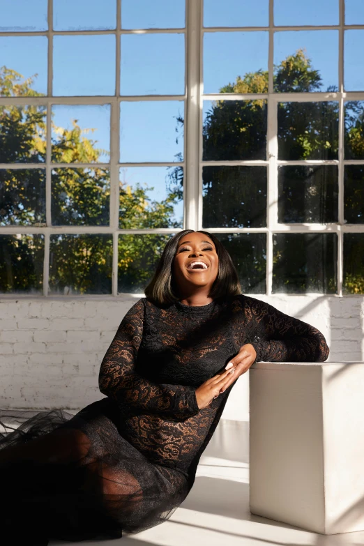 a woman in black posing by large windows